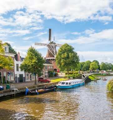 A windmill, canal and neighbouring buildings and trees in Friesland