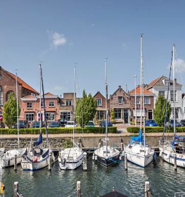 Boats in the harbour at Zealand facing a row of houses and cars