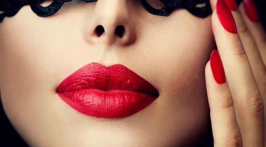 A woman in a black mask with red lips and red nails
