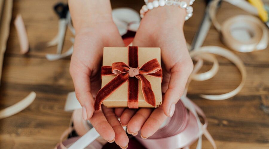 someone holding a small gift wrapped in a red ribbon